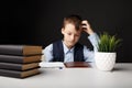Tired and depressed school boy sitting at the desk and studying alone. Royalty Free Stock Photo