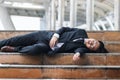 Tired depressed young Asian business man lying down on stairs and suffering from severe depression. Unemployment and layoff Royalty Free Stock Photo