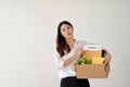 A tired and despairing Asian businesswoman holds a cardboard box with her resignation letter