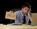 Tired desperate businessman in stress working at office computer desk holding sign asking for help Royalty Free Stock Photo
