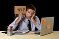 Tired desperate businessman in stress working at office computer desk holding sign asking for help Royalty Free Stock Photo