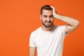 Tired dissatisfied young man in casual white t-shirt posing isolated on orange wall background, studio portrait. People Royalty Free Stock Photo