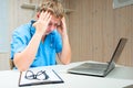 Tired Doctor holds aching head sitting in a the clinic