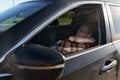 A tired driver sleeps in the car during the day, covered with a blanket and wearing a sleep mask over his eyes. Royalty Free Stock Photo