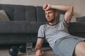 Tired after exercise and workout. Overtraining at home during selfisolation. Exhausted man sitting on floor breathing and resting Royalty Free Stock Photo