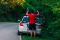 Tired exhausted biker puts his bike on a car to get a ride