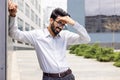 Tired and exhausted Indian young businessman standing near working offices outside and holding his hand, feeling pain Royalty Free Stock Photo