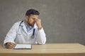 Tired exhausted male doctor sitting at the table after a hard day's work. Medical everyday life.