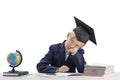 Tired exhausted schoolboy does his homework. Boy in school uniform and student hat sits at table next to notebooks and globe