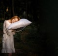 A tired, exhausted woman sleeps on a pillow she holds in her hands in the woods. Desire to sleep, time but rest concept. Place for