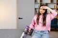 Tired and exhausted woman vacuuming house, cleaning rug carpet in living room, frustrated with doing much work about the house Royalty Free Stock Photo