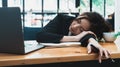 Tired or exhausted young business woman napping on working desk in front of her laptop in office Royalty Free Stock Photo