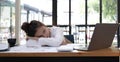 Tired or exhausted young business woman napping on working desk in front of her laptop in office Royalty Free Stock Photo