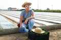 Tired farm worker sits on log after covering plants with covering material