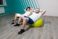Tired fat man is lying on a fitness ball training during group fitness classes. Overweight