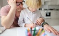 Tired father helping school boy with ADHD do his homework at home. Homeschooling, distance learning, online studying, remote Royalty Free Stock Photo