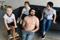 tired father with laptop and little kids sitting on sofa around Royalty Free Stock Photo