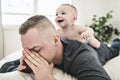 Tired father sleep but his baby boy interferes him. Young happy father lying on bed while his son play with him Royalty Free Stock Photo