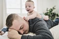 Tired father sleep but his baby boy interferes him. Young happy father lying on bed while his son play with him Royalty Free Stock Photo