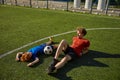 Tired father and son soccer player lying on grass of football field