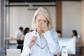 Tired fatigued senior female employee taking off glasses feeling eyestrain