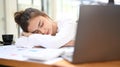 Tired female office worker having a nap at her desk with her head lying on her arm, tired from work Royalty Free Stock Photo