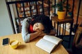 Tired female student sleeps at the table in cafe Royalty Free Stock Photo