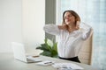 Tired female worker stretching in chair relaxing after working d