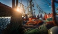 Tired fishermen team working on a trawler boat in the open sea during the evening sunset hours, using wet fishing nets, ropes, and Royalty Free Stock Photo