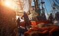 Tired fishermen team working on a trawler boat in the open sea during the evening sunset hours, using wet fishing nets, ropes, and Royalty Free Stock Photo