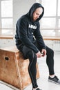 Tired fit man wearing hoodie relaxing after hard training box at light hall Royalty Free Stock Photo