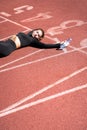 Tired fit woman in sportswear resting after workout or running on a treadmill rubber stadium, holding a bottle of water, taking a Royalty Free Stock Photo