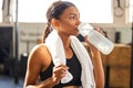 Tired, fitness or Indian woman drinking water at gym in training, workout or exercise to hydrate her body. Fatigue