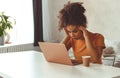 Frustrated African descent young woman in front of laptop at home, receiving e-mail with bad news Royalty Free Stock Photo