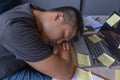 Young freelancer fall asleep on laptop at unorganized workplace