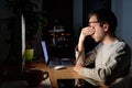 Tired freelancer man rubbing his eyes, sitting at desktop PC at night, remote work at home, falls asleep from fatigue Royalty Free Stock Photo