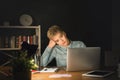 Tired freelancer working on laptop at home until late evening Royalty Free Stock Photo