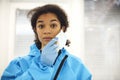 Tired frustrated female african american medical worker in protective gear taking off face mask Royalty Free Stock Photo