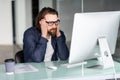 Tired or frustrated young man working in office looking at computer screen Royalty Free Stock Photo