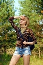 Attractive girl in camo shirt, jeans shorts with backpack on hiking trail in forest Royalty Free Stock Photo