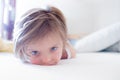 Tired girl daughter doesn`t want to wake up looking at camera on parent`s bed at morning. Happy relaxed family life with Royalty Free Stock Photo