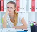 Tired girl sits propped head in his hands at a desk in the office. Royalty Free Stock Photo
