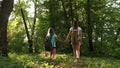 Tired girls travelers with backpacks go through the thicket in the forest. Hiker woman walks in the forest. happy hiker