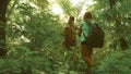 Tired girls travelers with backpacks go through the thicket in the forest. Hiker woman walks in the forest. happy hiker