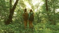 Tired girls travelers with backpacks go through the thicket in the forest. Hiker woman walks in the forest. happy hiker