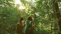 Tired girls travelers with backpacks go through the thicket in the forest. Hiker woman walks in the forest. happy hiker