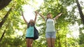 Tired girls travelers with backpacks go through the thicket in the forest. Hiker woman walks in the forest. happy hiker