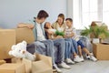 Tired happy family with two kids resting sitting on sofa among boxes during moving in new house. Royalty Free Stock Photo