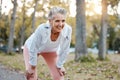 Tired, happy and senior woman running in outdoor nature park for retirement health, wellness and fitness workout