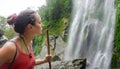 Tired, but happy young woman hiker looking at a waterfall jungle